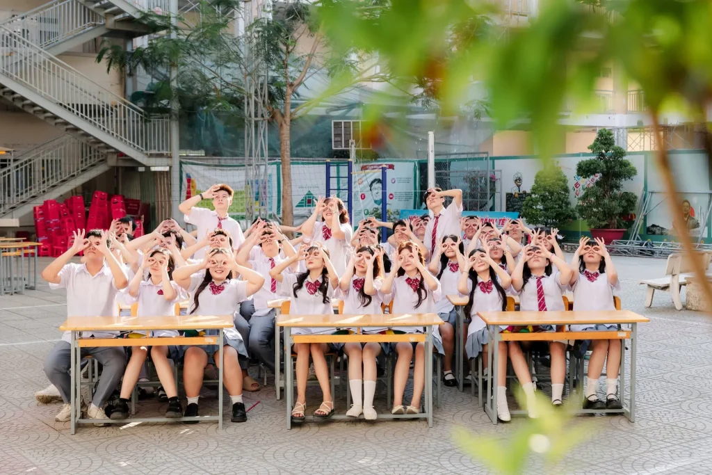 Ảnh cả lớp ngồi và đứng quanh bàn học giữa sân trường