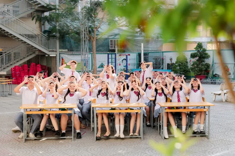 Ảnh cả lớp ngồi và đứng quanh bàn học giữa sân trường