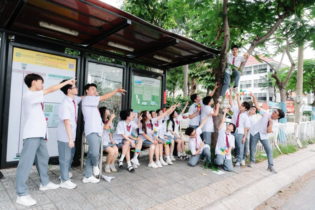 Nhóm học sinh mặc đồng phục đứng cùng nhau tại hành lang có mái che