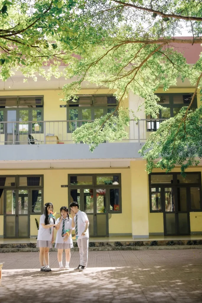 Một tiết học ở lại trong ảnh – Kỷ yếu lớp học và hành lang 10 Ba người đứng dưới tán cây trước dãy lớp học