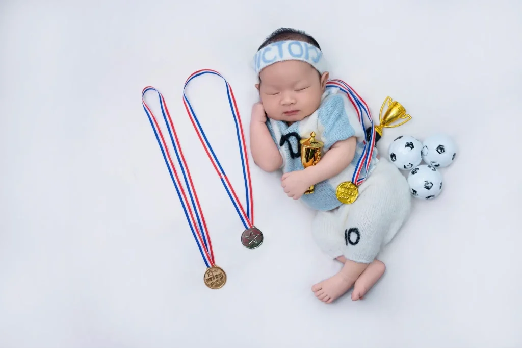 Ảnh newborn: bé nằm ngủ với đạo cụ thể thao