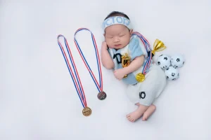Ảnh newborn: bé nằm ngủ với đạo cụ thể thao