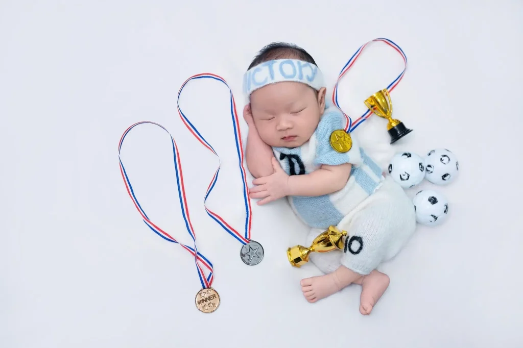 Chụp ảnh bé sơ sinh và bé chưa biết ngồi: phân biệt trước khi chọn tư thế 4 Ảnh newborn: bé nằm ngủ với đạo cụ thể thao