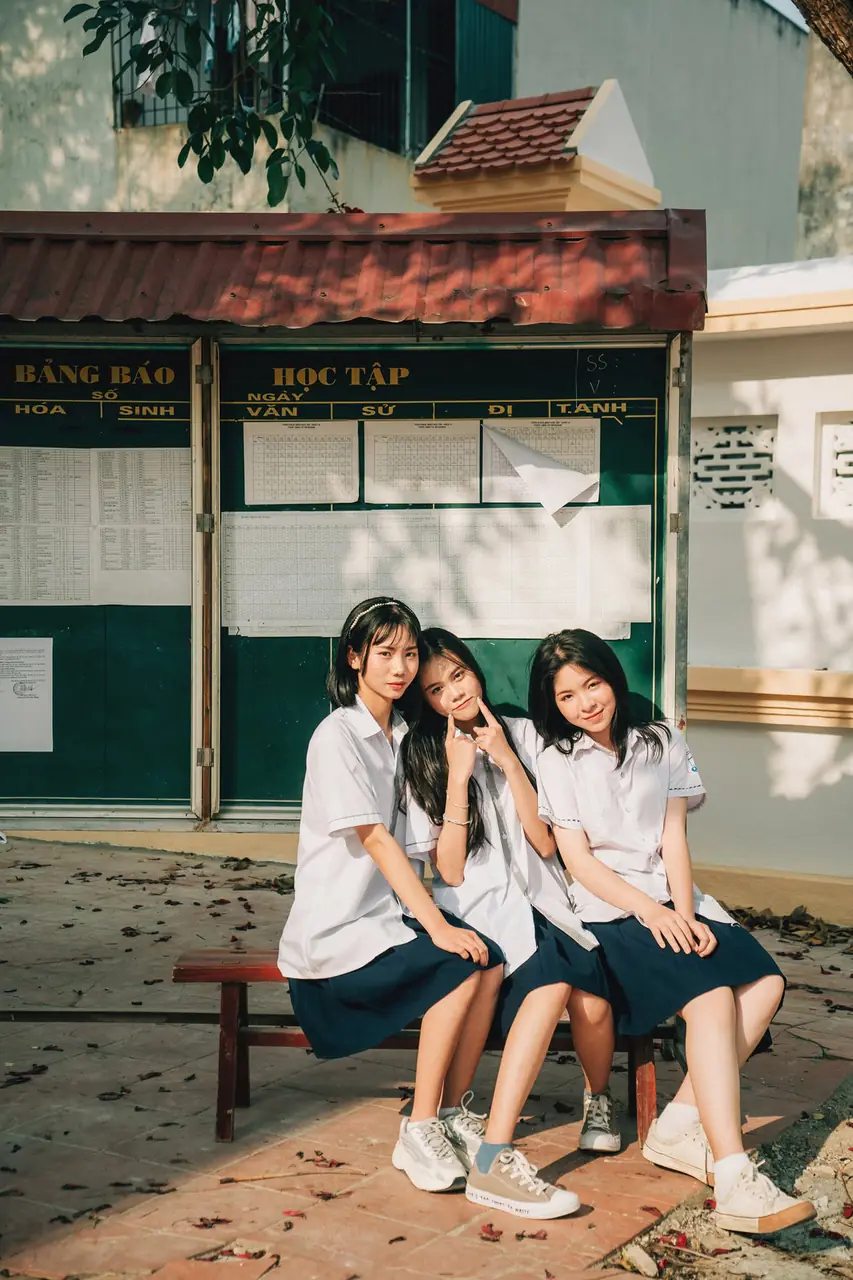 Ba nữ sinh ngồi trên bậc thềm nhà cũ
