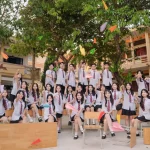 Tập thể lớp mặc đồng phục trắng chụp ảnh dưới tán cây