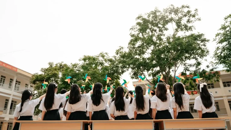 Cả lớp ngồi trên ghế và giơ chong chóng giữa sân trường