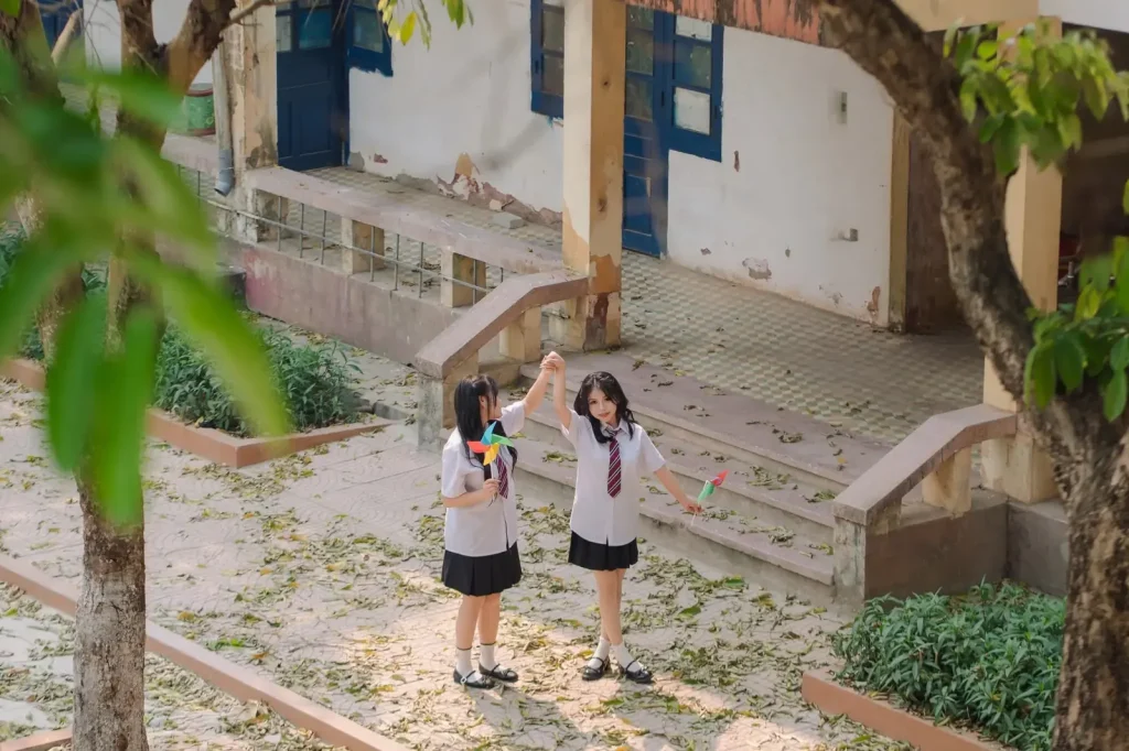 Hai bạn nữ cầm chong chóng trước thềm lớp học