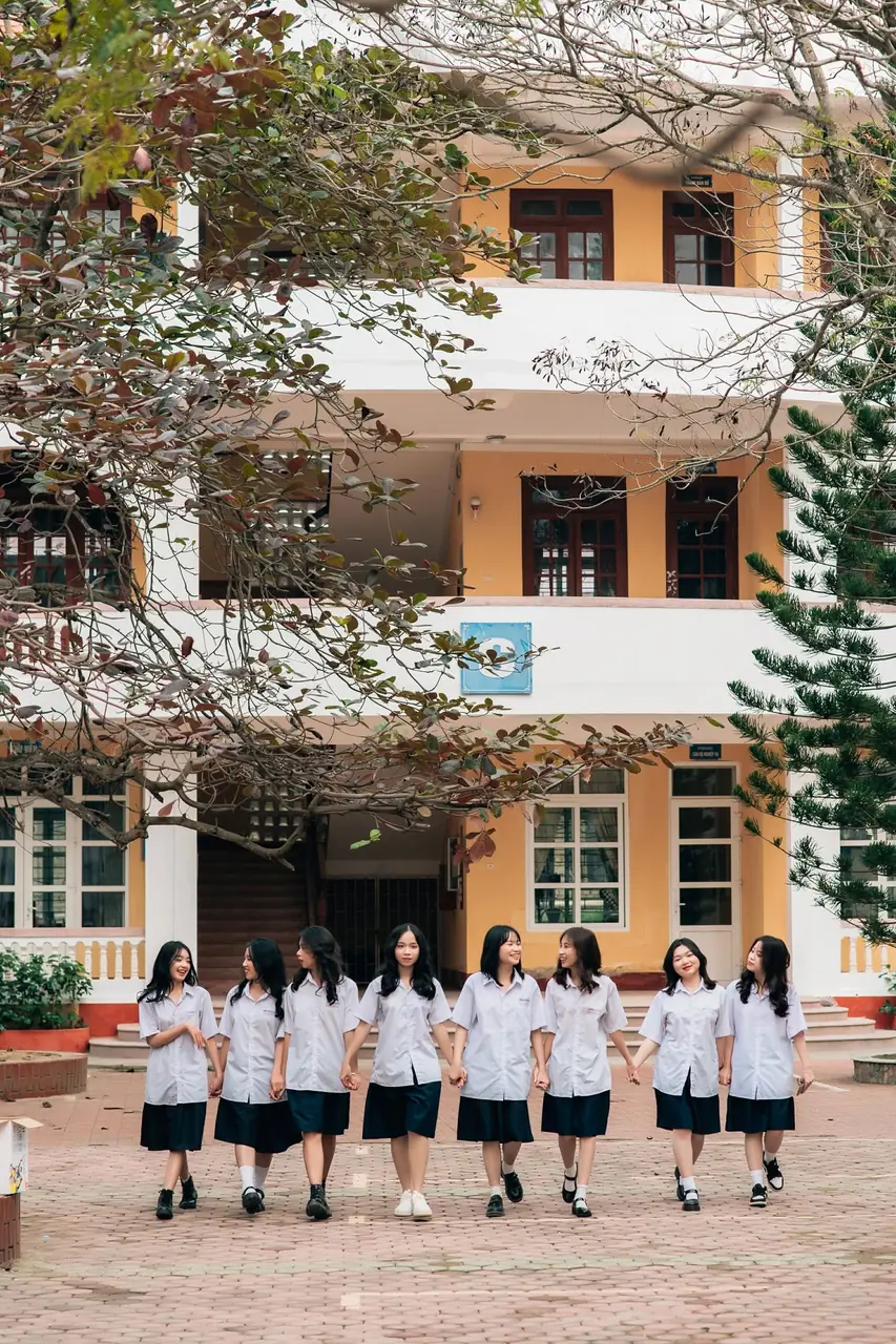Góc sân trường với cây xanh và nhóm nữ sinh