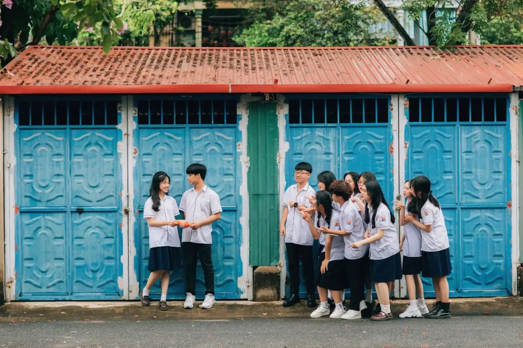 Học sinh đồng phục trước cửa gỗ xanh