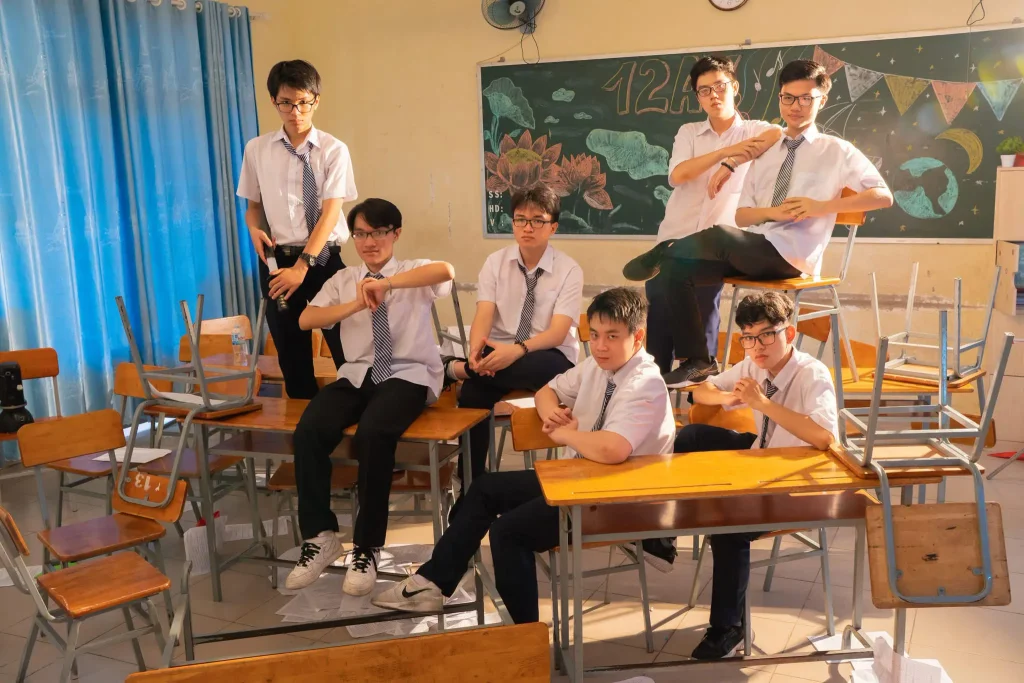 Nhóm học sinh tạo dáng bên bàn học và bảng lớp trang trí
