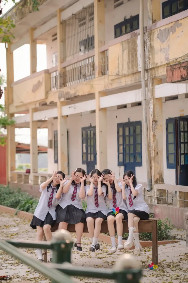 Nhóm bạn nữ mặc đồng phục ngồi cùng nhau trên ghế gỗ