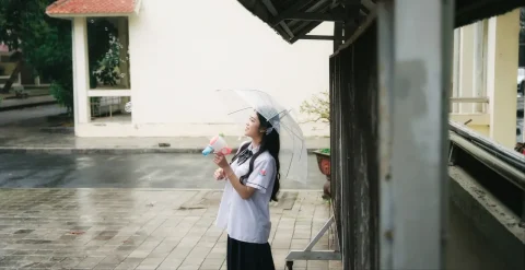 Nữ sinh cầm máy ảnh trong sân trường