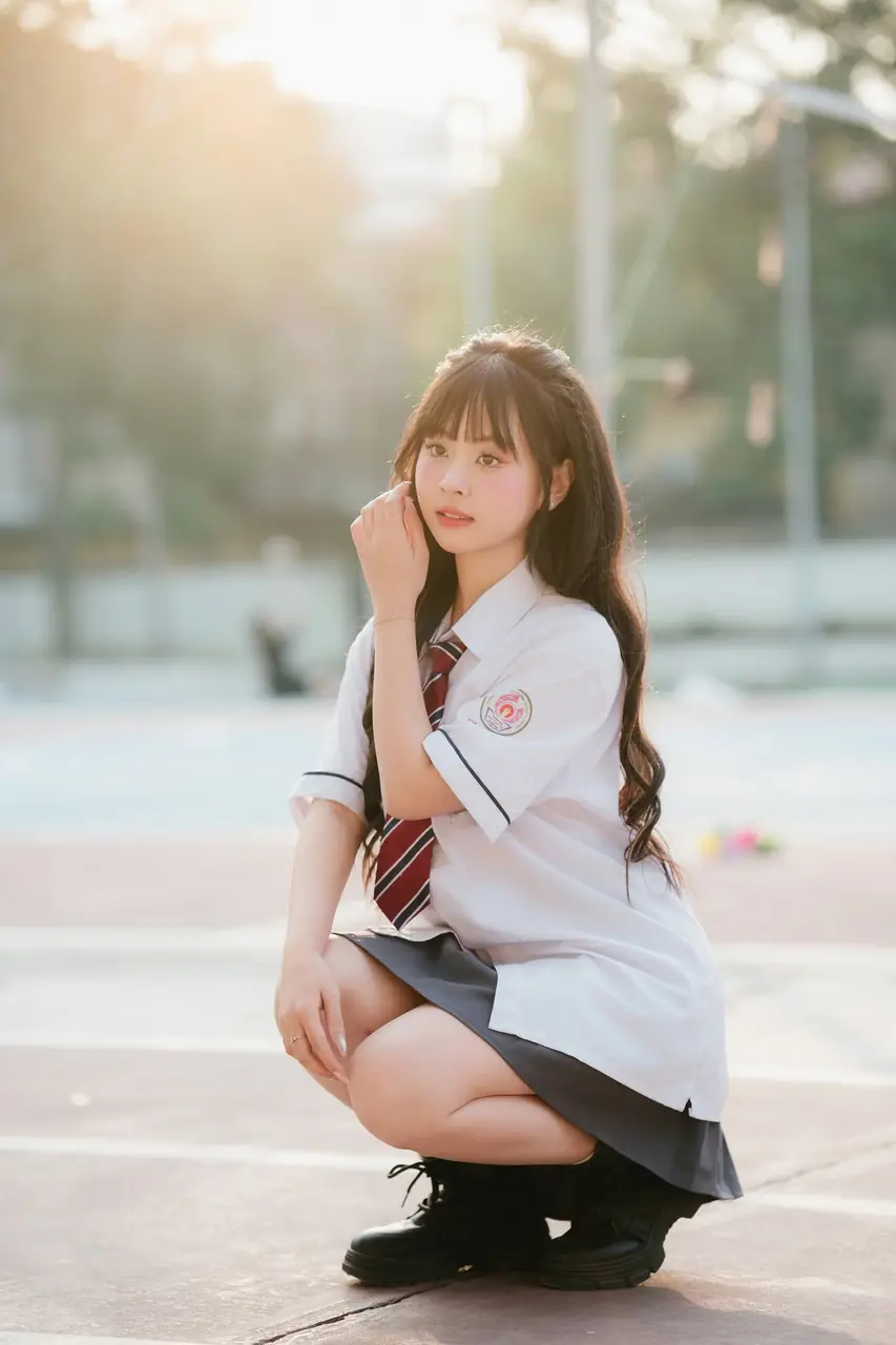 Nữ sinh ngồi thấp trên sân trường với đồng phục trắng