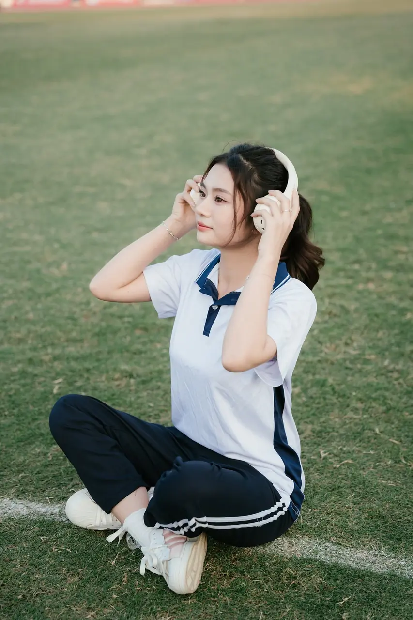 Nữ sinh ngồi trên cỏ mặc đồng phục trắng