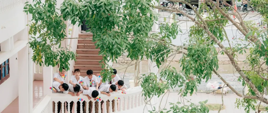 Nữ sinh nhìn qua cửa sổ có cây xanh