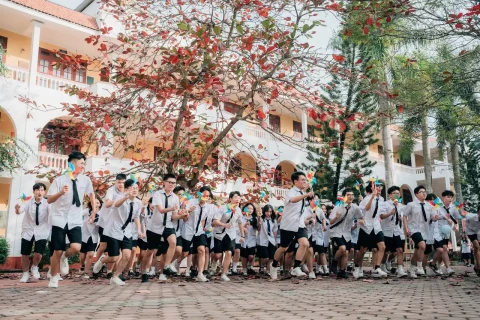 Tập thể lớp đồng phục dưới cây đang ra hoa