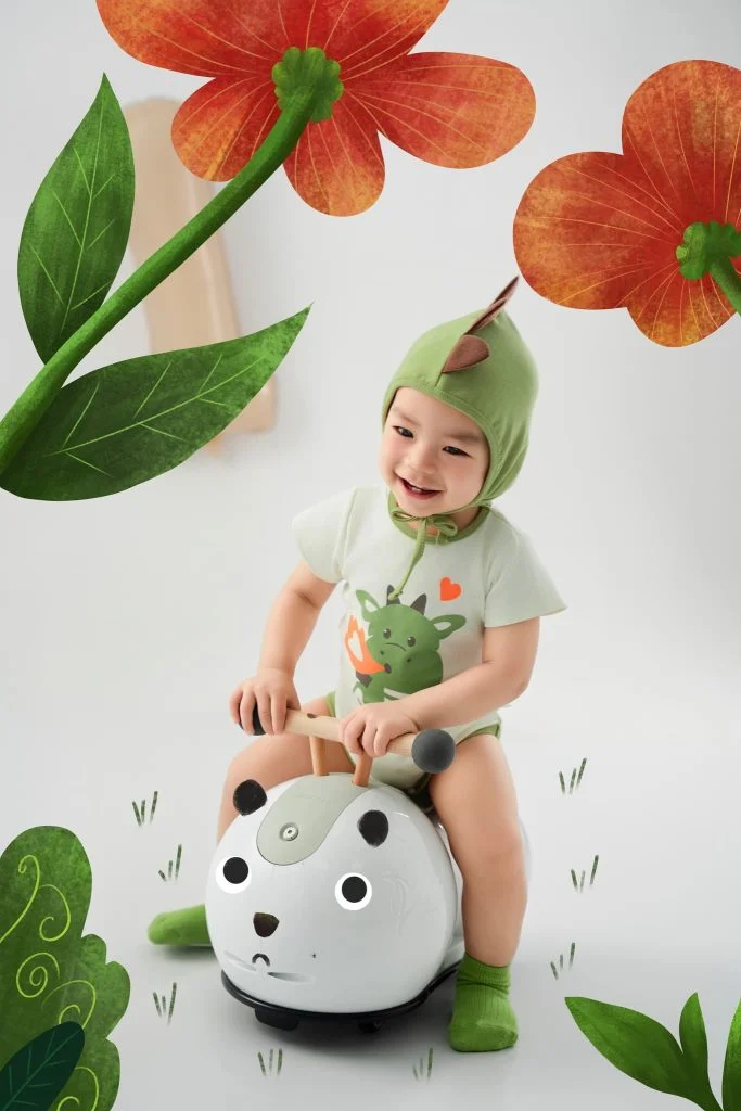 Bé ngồi trên đạo cụ chấm bi trong bối cảnh cây lá minh họa