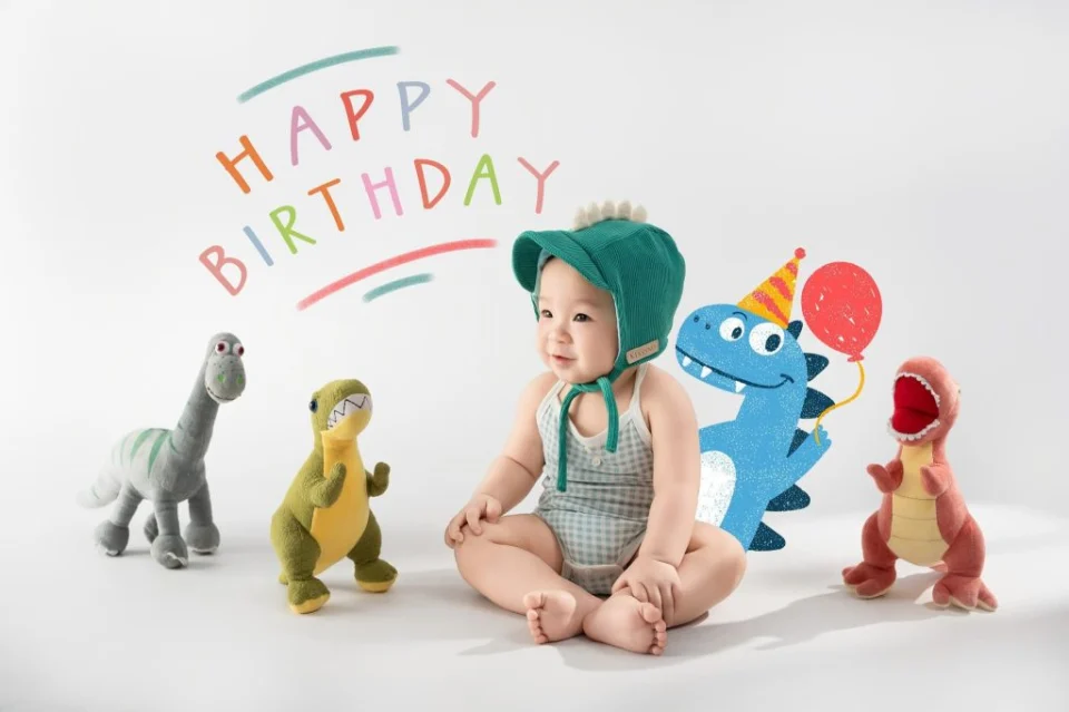 Bé ngồi cùng các mô hình khủng long trong ảnh sinh nhật