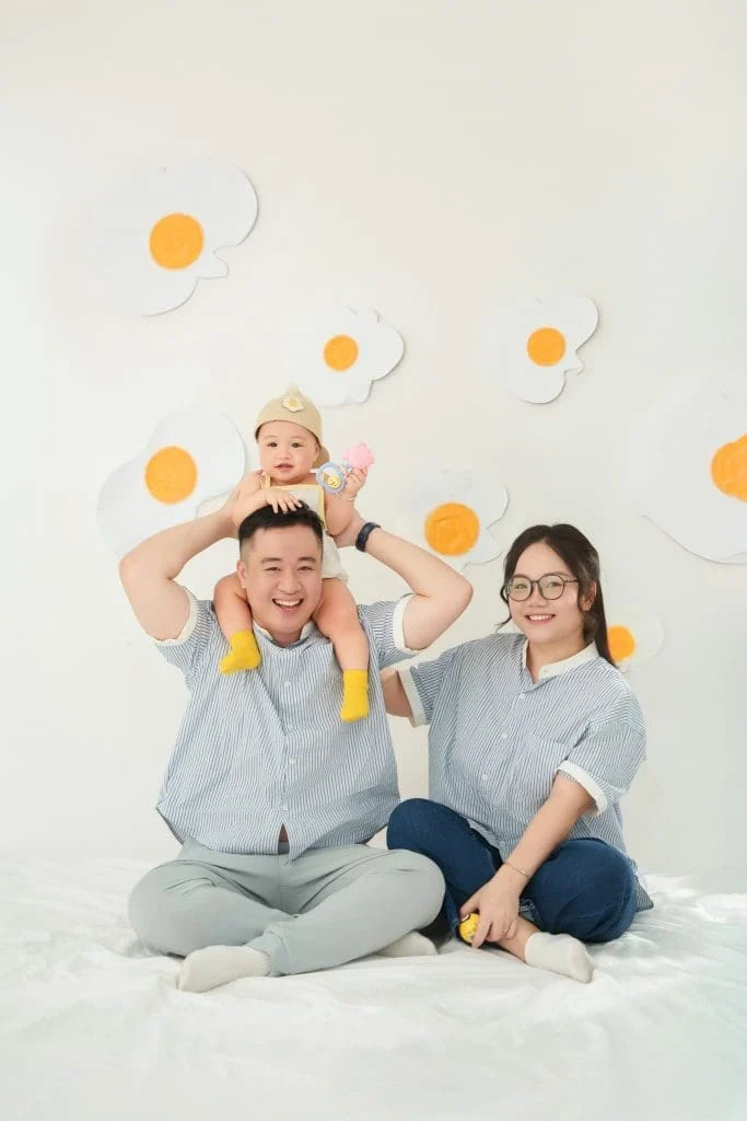 Gia đình có bé chụp ảnh cùng nhau trên nền sáng với các chi tiết màu cam