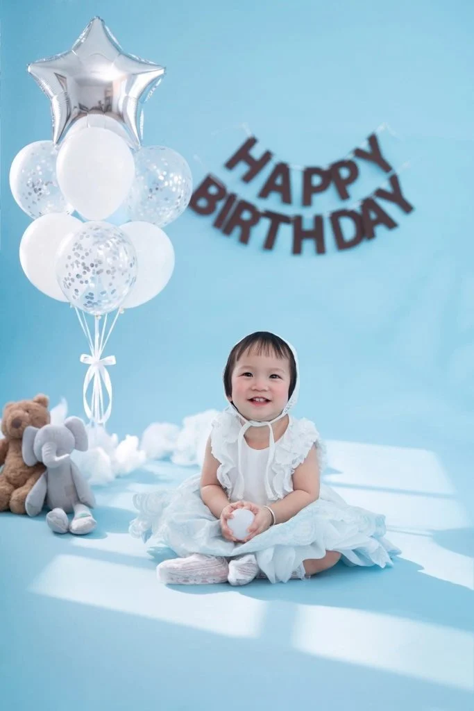 Bé ngồi trên nền sáng trong bối cảnh sinh nhật một tuổi