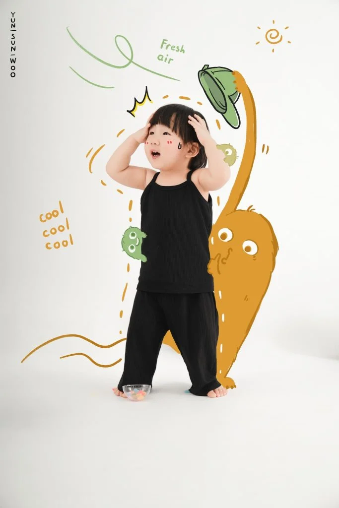 Bé trai mặc đồ đen đứng trước bối cảnh minh họa con vật