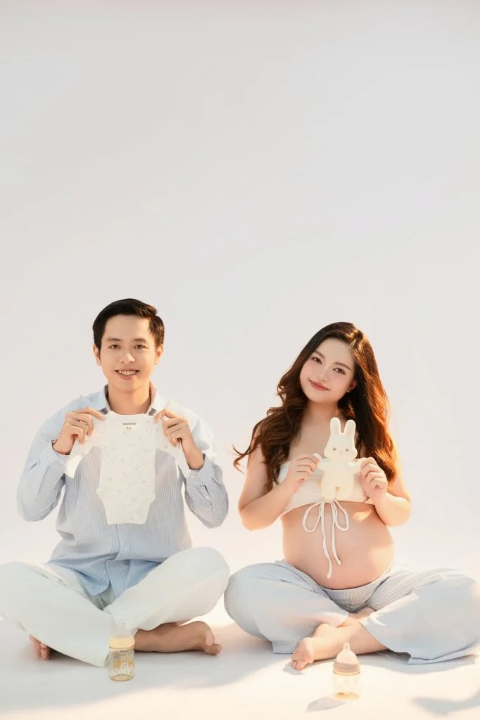 Mẹ bầu và bạn đời ngồi tạo dáng vui trong studio
