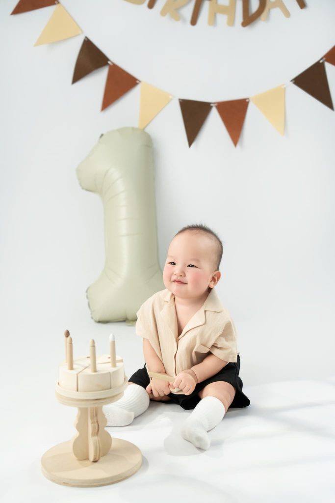 Bé ngồi bên bánh và bóng số một trong ảnh sinh nhật