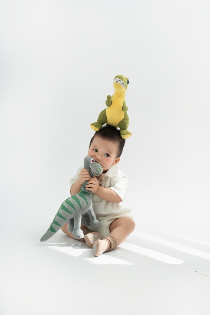 Bé ngồi cùng các mô hình động vật trong bối cảnh sáng