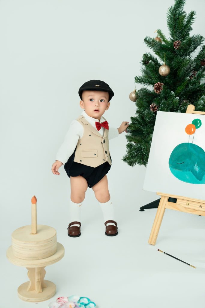 Bé đứng bên giá vẽ trong bối cảnh Giáng sinh