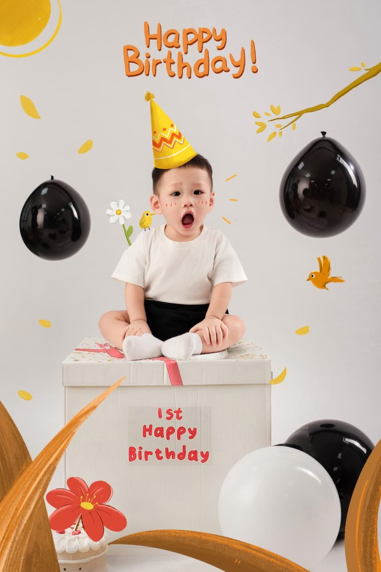 Bé đội mũ sinh nhật ngồi sau mô hình bánh trên nền trắng
