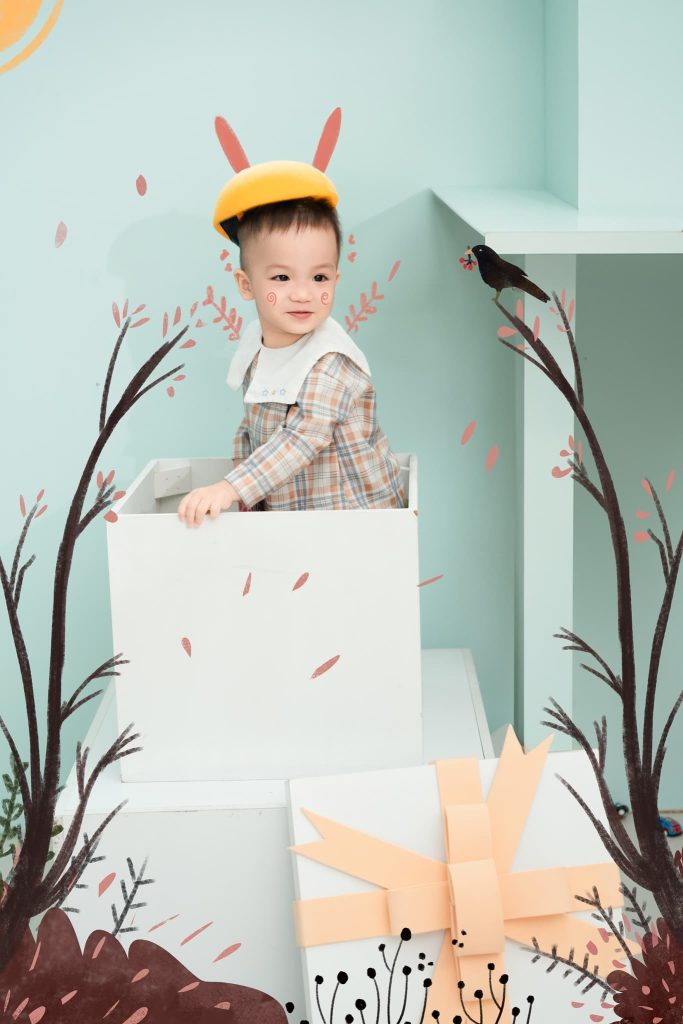 Bé đội mũ tai thỏ tạo dáng trong bối cảnh cây lá