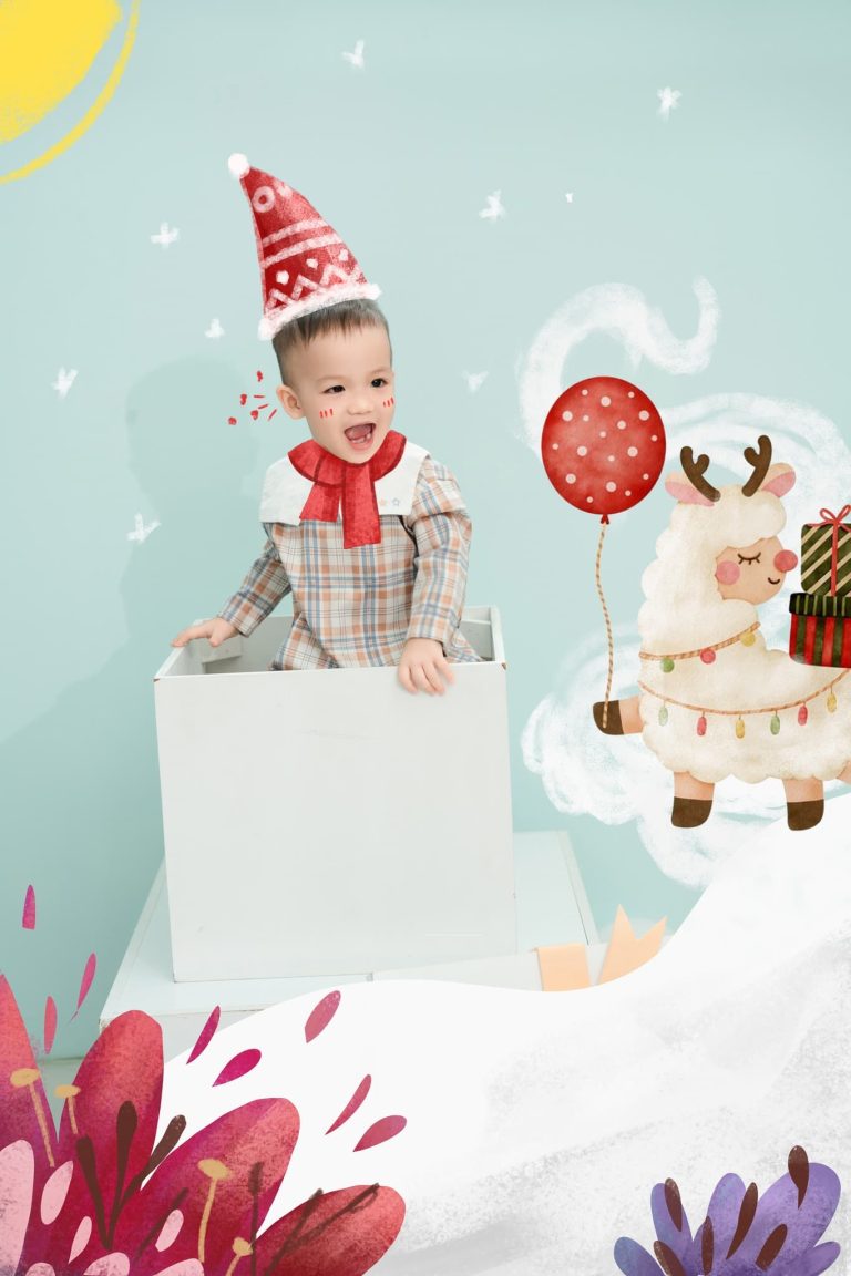 Bé đội mũ đỏ bên bánh và kẹo trang trí trong concept sinh nhật