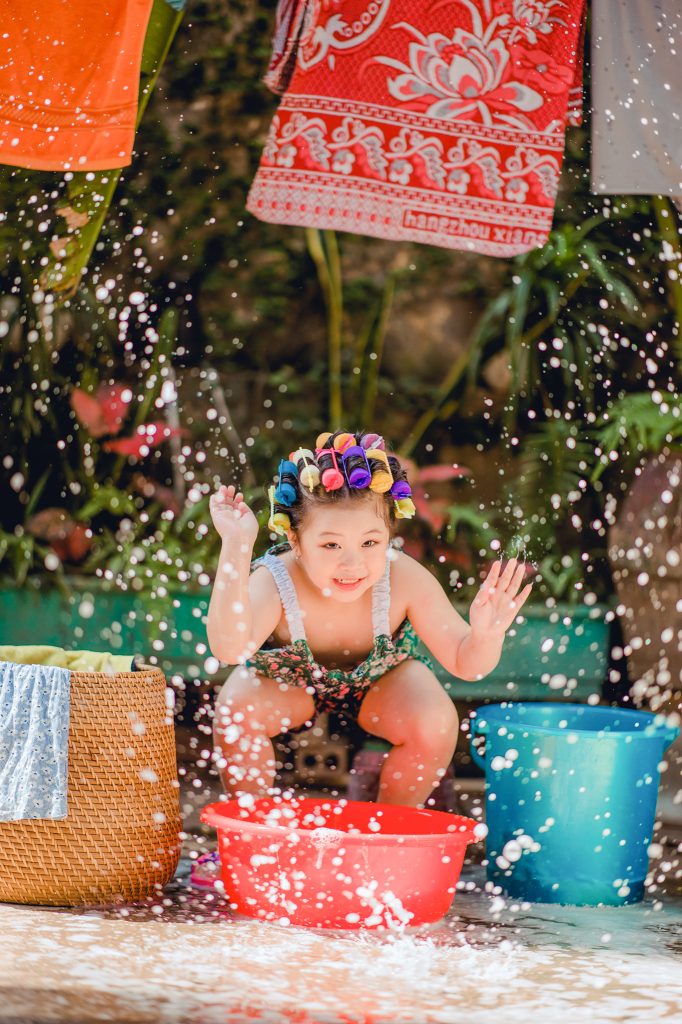 Bé cúi về phía chậu giặt giữa những giọt nước