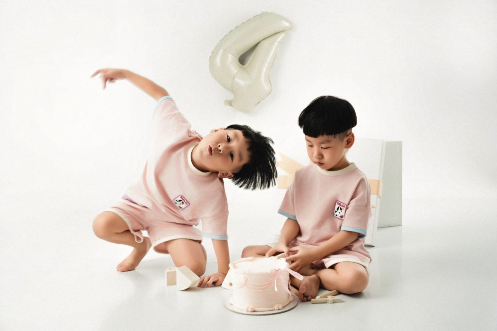 Hai bé mặc đồ hồng bên chiếc bánh sinh nhật số bốn