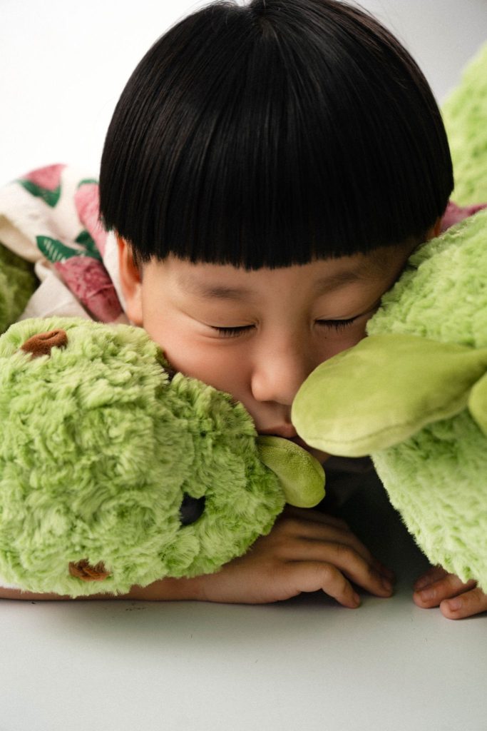 Bé ôm khủng long bông lớn trên nền sáng