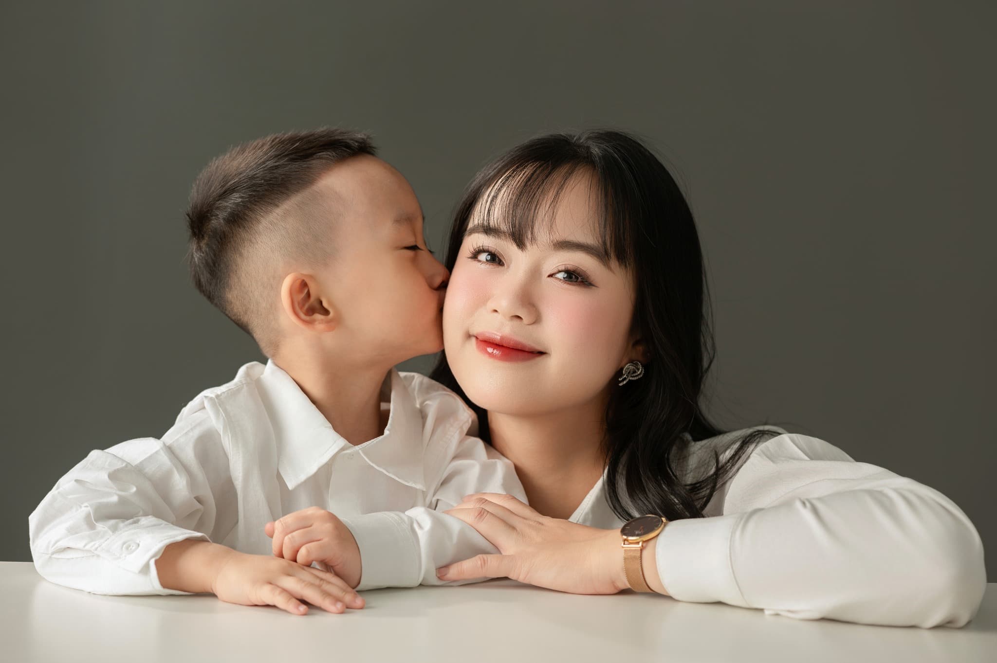 Bé trai áo trắng hôn lên má mẹ