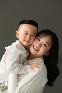 Mẹ và bé tựa vào nhau trong bộ ảnh gia đình nền tối