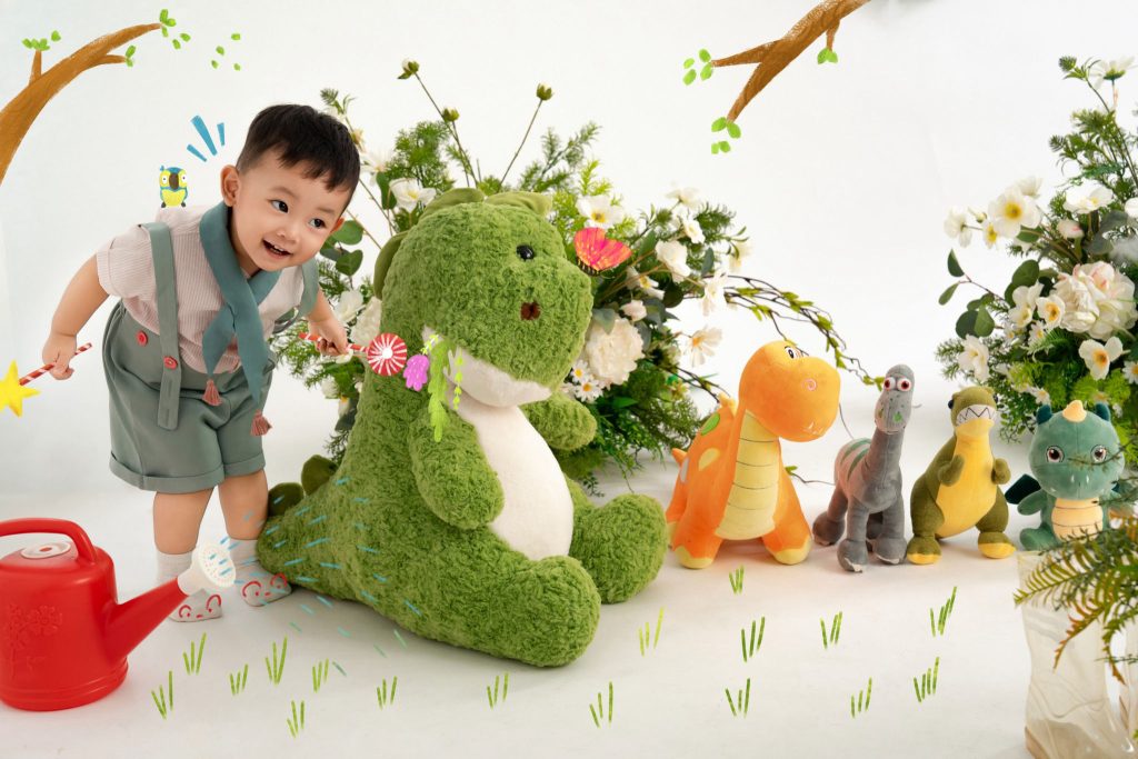 Bé tựa cạnh khủng long bông xanh trong bối cảnh Noel minh họa