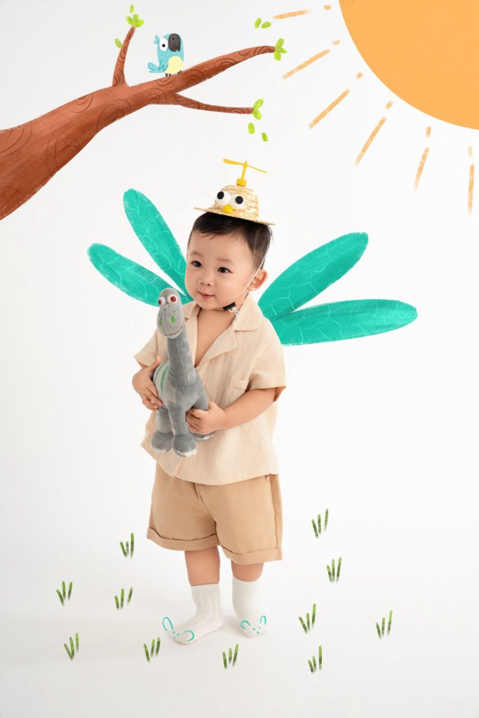 Bé ôm thú bông dưới cây minh họa và đôi cánh cổ tích