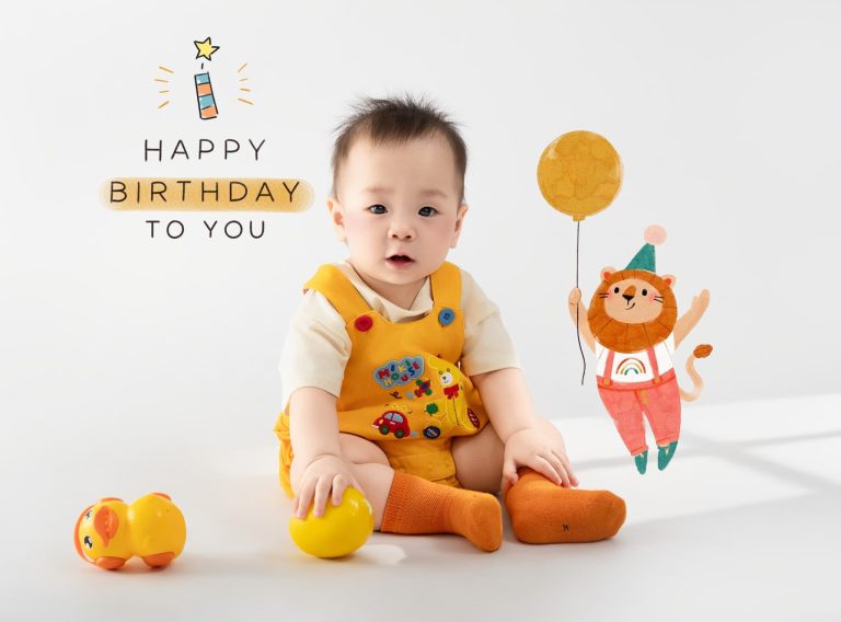 Bé mặc đồ vàng ngồi cùng quả cam trong ảnh thôi nôi