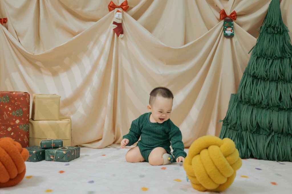 Bé ngồi trong bối cảnh Giáng sinh màu xanh và vàng