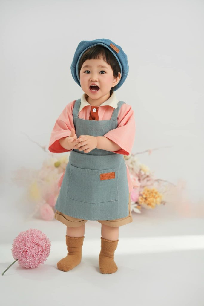 Lên concept riêng cho bé: từ một sở thích đến kế hoạch chụp cụ thể 1 Bé chắp tay trước ngực, đội mũ xanh và mặc áo màu san hô