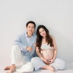 Mẹ bầu và bạn đời ngồi bên nhau trên nền trắng