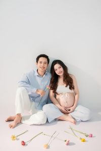 Mẹ bầu và bạn đời ngồi bên nhau trên nền trắng