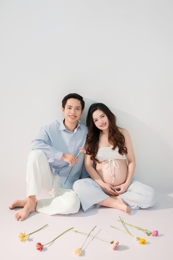 Mẹ bầu và bạn đời ngồi bên nhau trên nền trắng