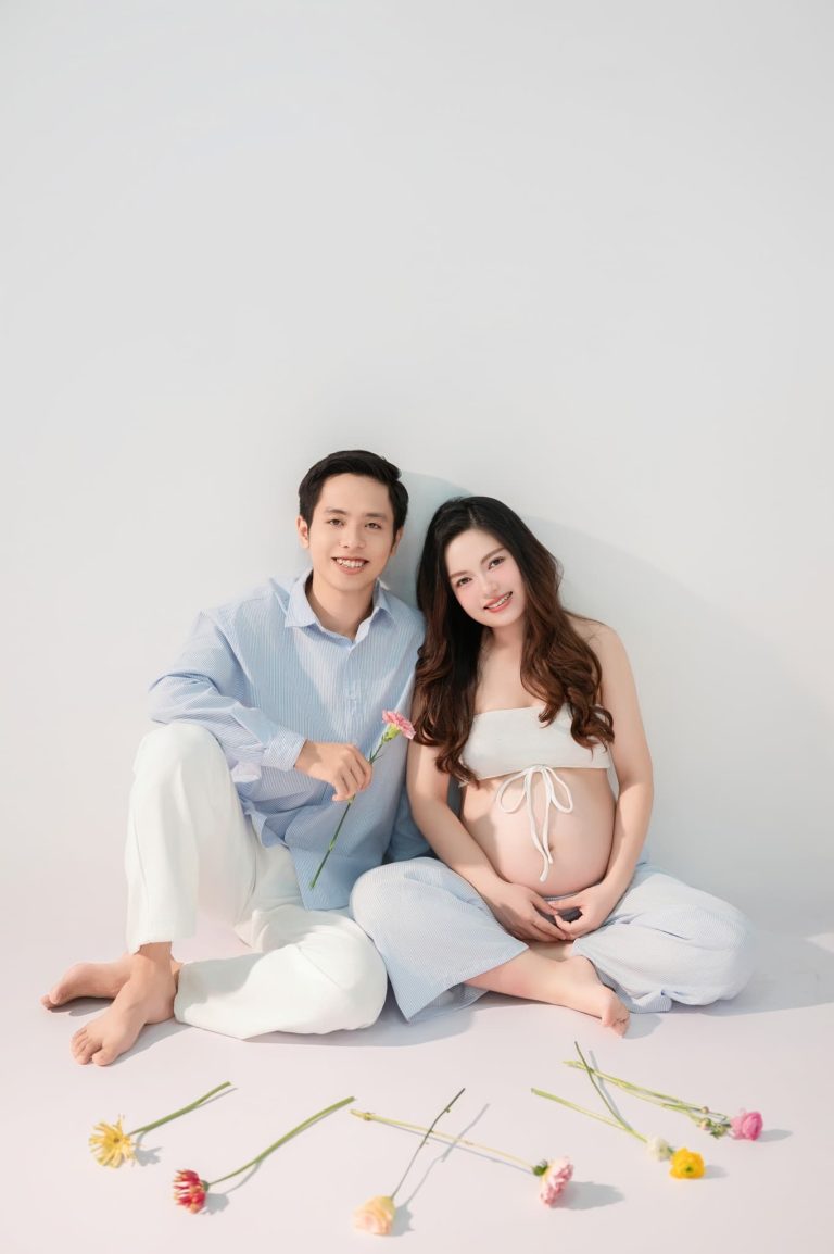 Mẹ bầu và bạn đời ngồi bên nhau trên nền trắng