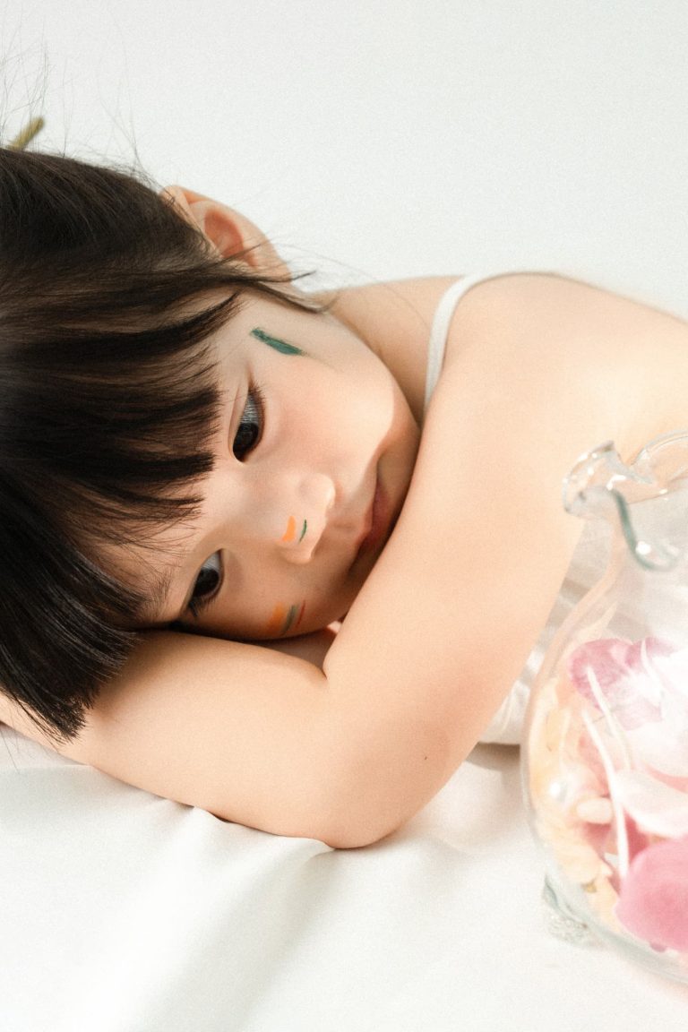 Ảnh cận bé tựa đầu lên tay trong bối cảnh sáng màu