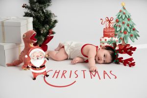 Bé nằm giữa các phụ kiện Giáng sinh trên nền sáng