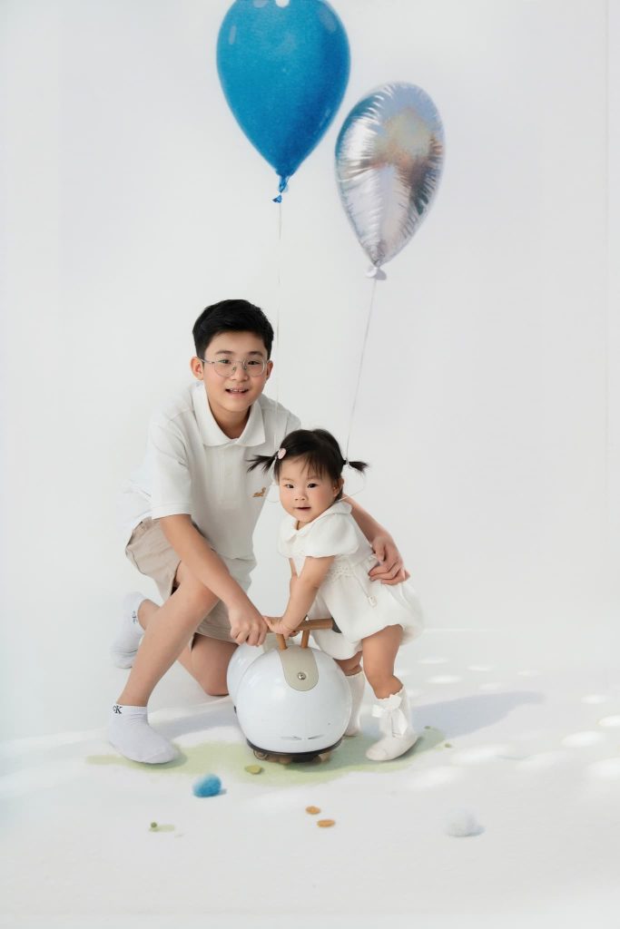 Bố ngồi phía sau bé, cả hai bên quả bóng trắng lớn