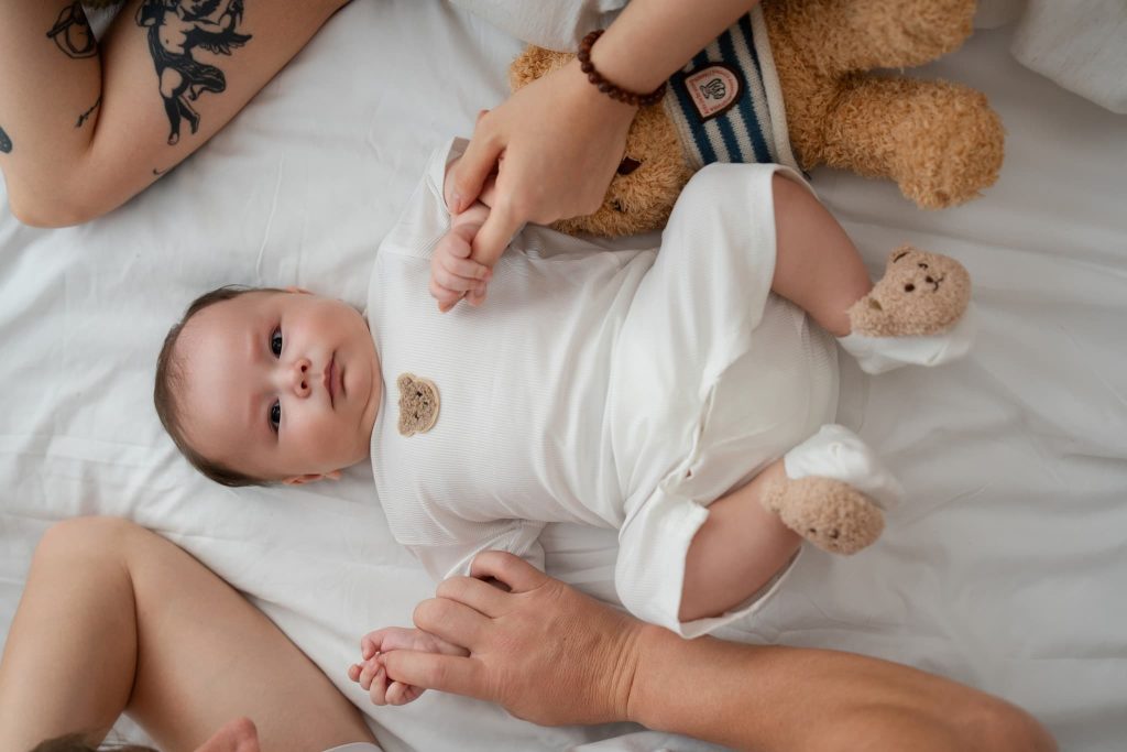Mẹ cúi nhìn bé nằm trên giường ở nhà